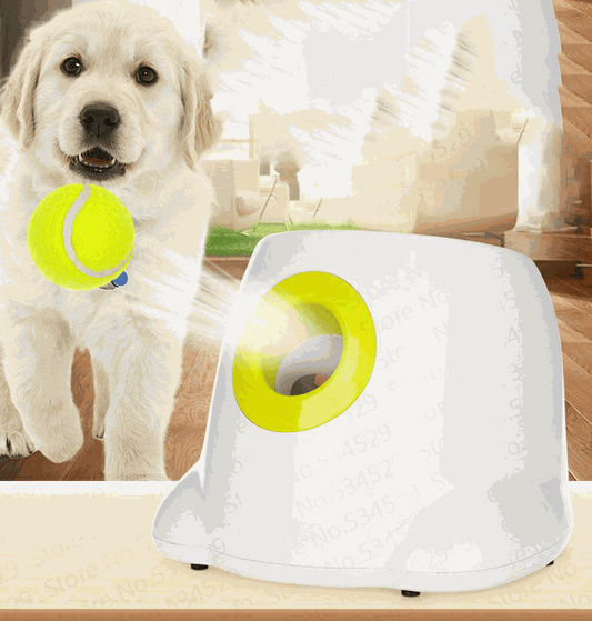 Automatic Ball Launcher for Dogs in white plastic with a bright yellow loading rim, pictured beside a puppy holding a tennis ball
