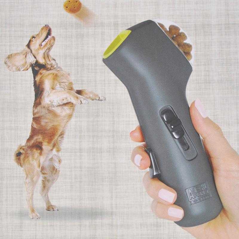 Pet Treat Launcher in charcoal grey plastic with lime-green accent, sliding black trigger, and a treat visible in the barrel.