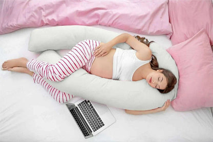 Sleep Therapy Pillow in white with a contoured ergonomic shape, supporting a woman curled on her side in striped pyjamas
